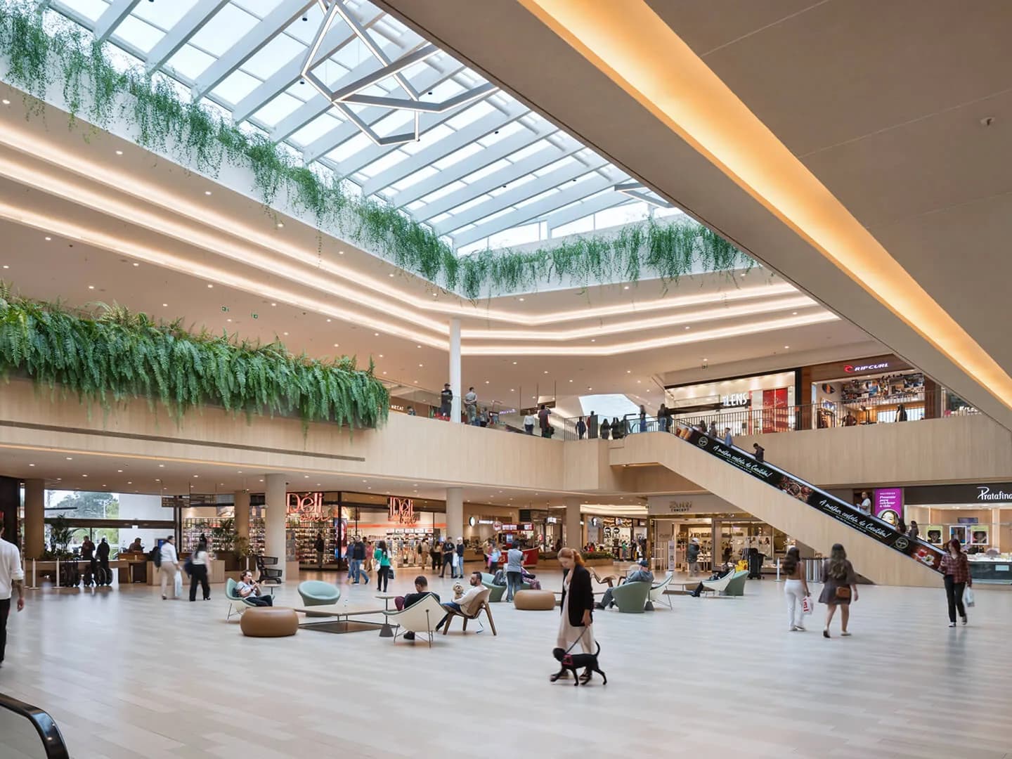 Corredor de shopping com lojas e clientes circulando